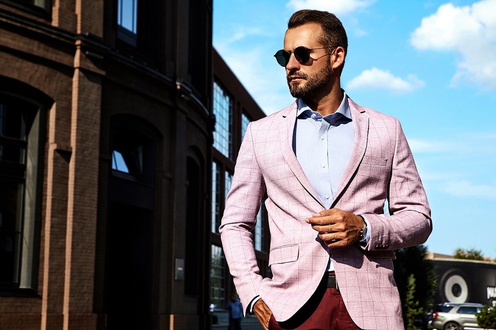 Portrait of sexy handsome fashion businessman model dressed in elegant suit posing on street background. Metrosexual